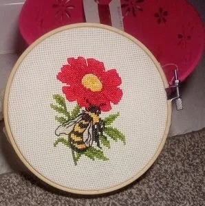 Red flower and bee cross stitch in a hoop, finished by a customer