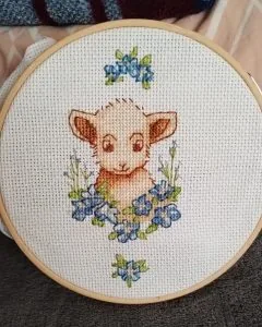 Lamb and forget-me-nots cross stitch in a hoop, finished by a customer